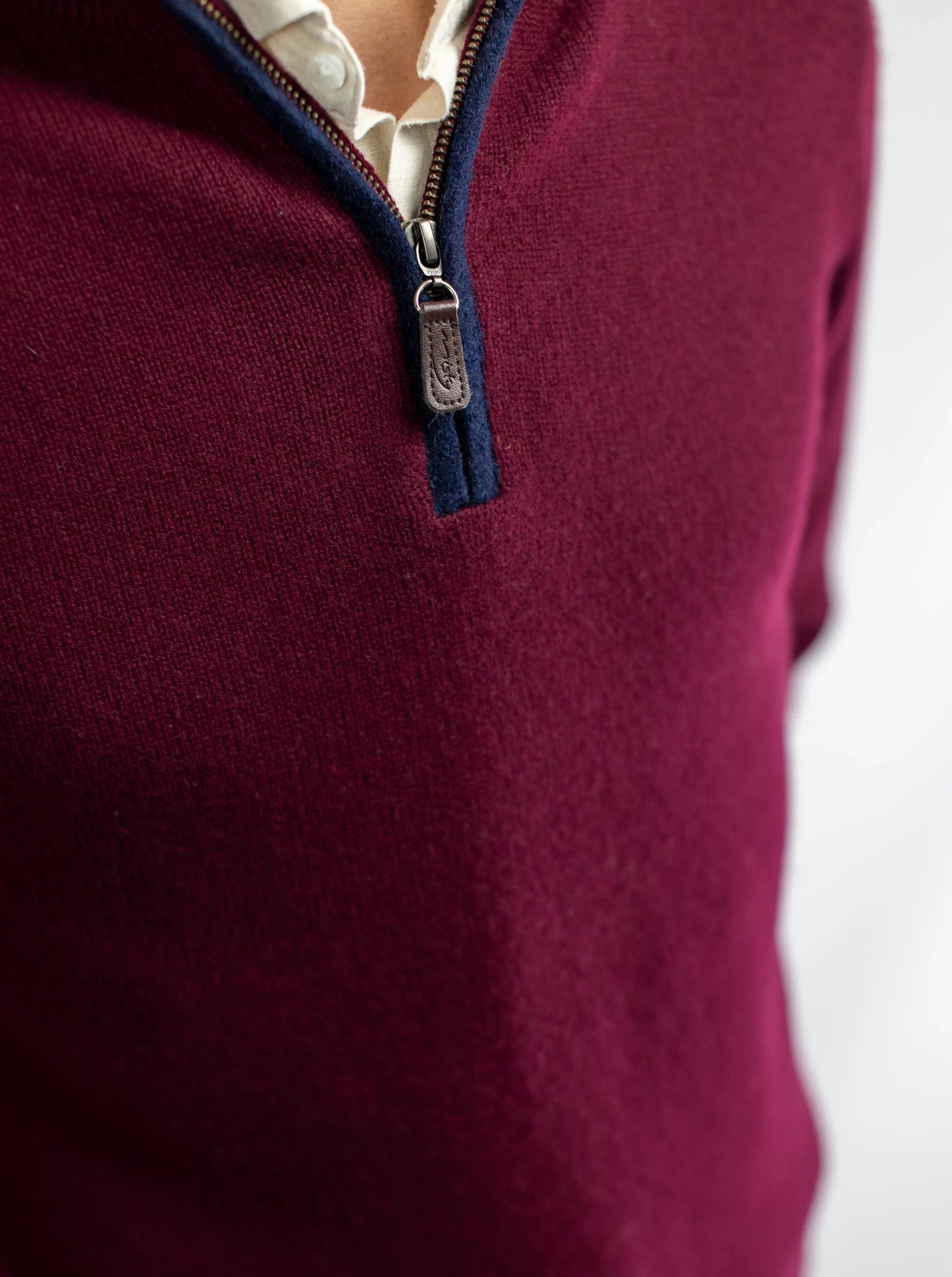 Detail of zip neck jumper from Misty Cashmere in burgundy wine with navy boiled wool trim