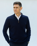 Man wearing a fine knit navy blue cashmere quarter-zip sweater over a white shirt against a light blue background
