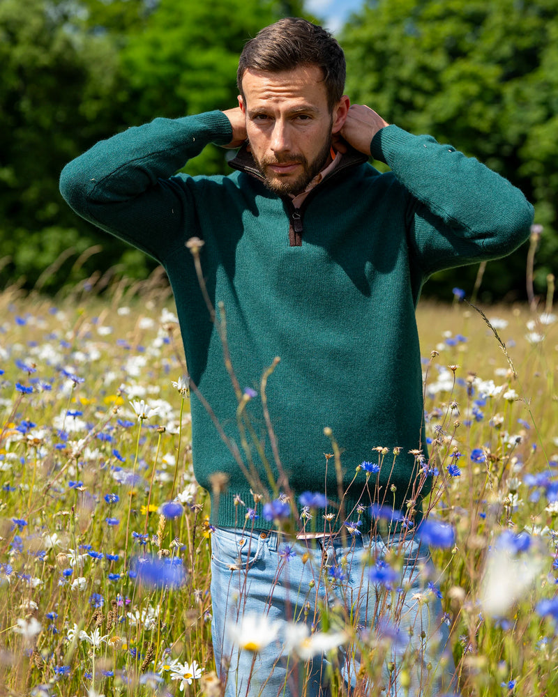 Male wearing green cashmere and merino zip neck jumper in meadow
