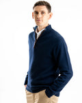 Man wearing a navy cashmere sweater over a white shirt on a white background