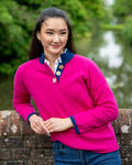 Woman wearing a bright pink cerise sweater with blue collar and cuffs, standing outdoors.