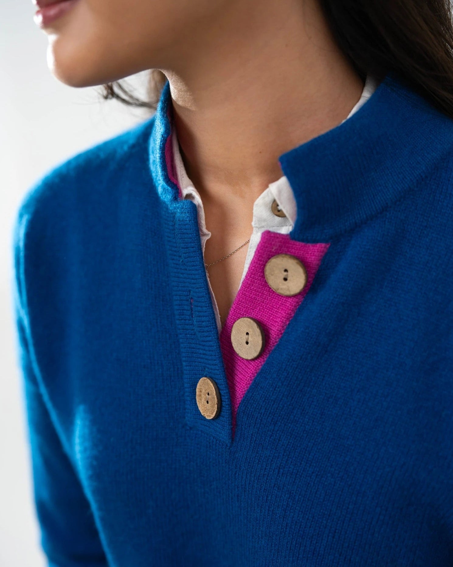 Women's high collar cashmere jumper in blue with pink details and coconut buttons