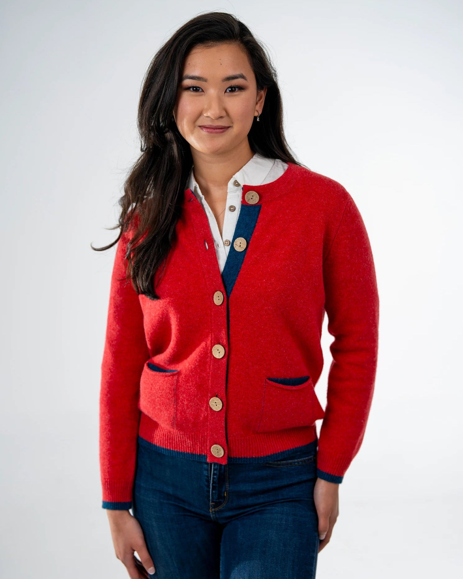 Woman wearing orange cashmere cardigan with navy pockets with white background