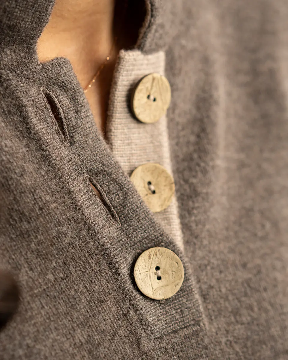 detail of opening on high collar jumper in brown and beige with large coconut buttons by misty cashmere