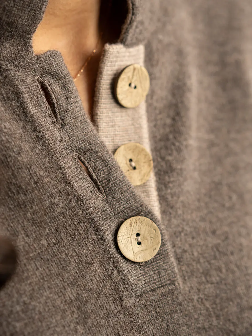 detail of opening on high collar jumper in brown and beige with large coconut buttons by misty cashmere