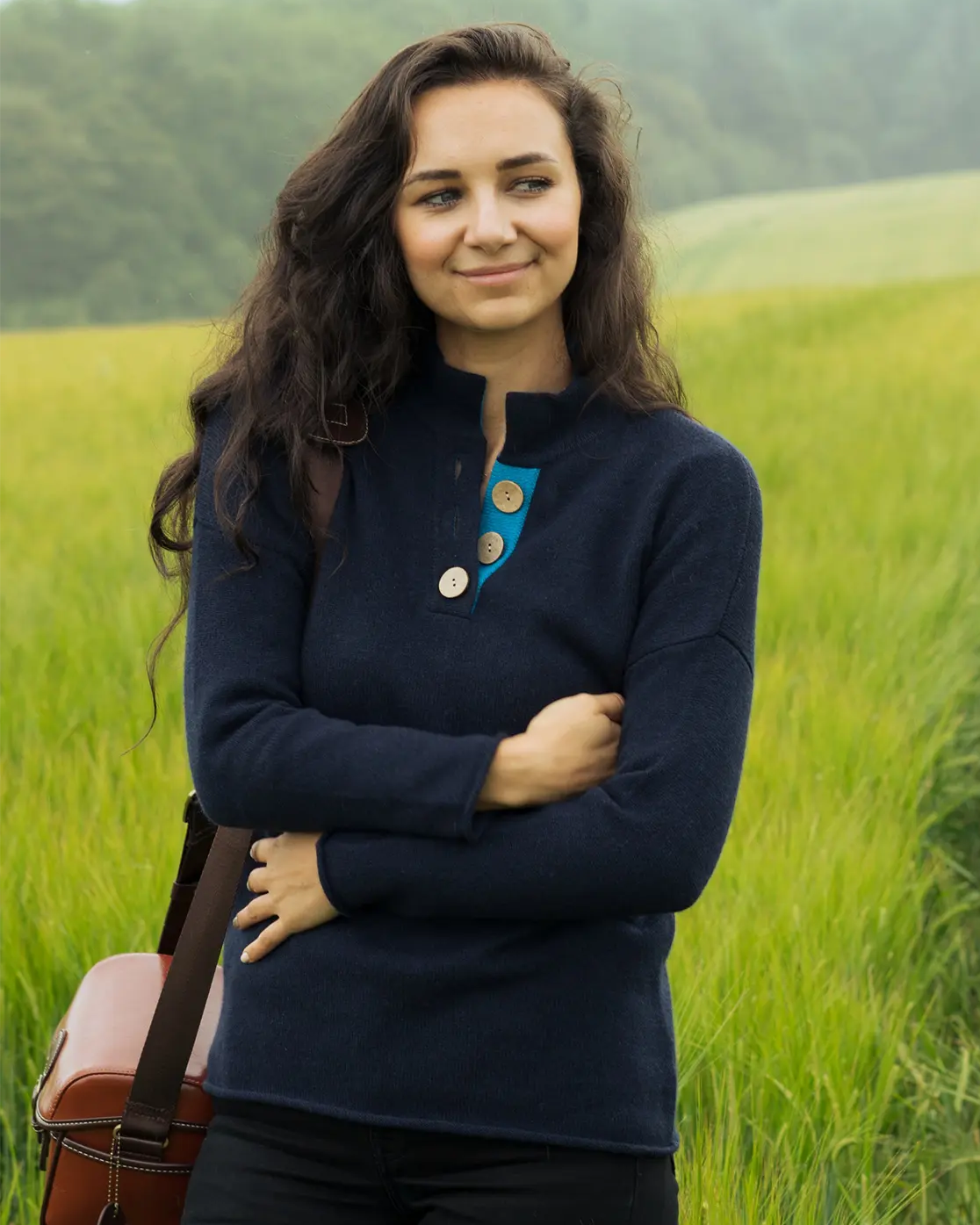 model standing in a field wearing  the navy and turquoise high collar jumper sweater from Misty Cashmere