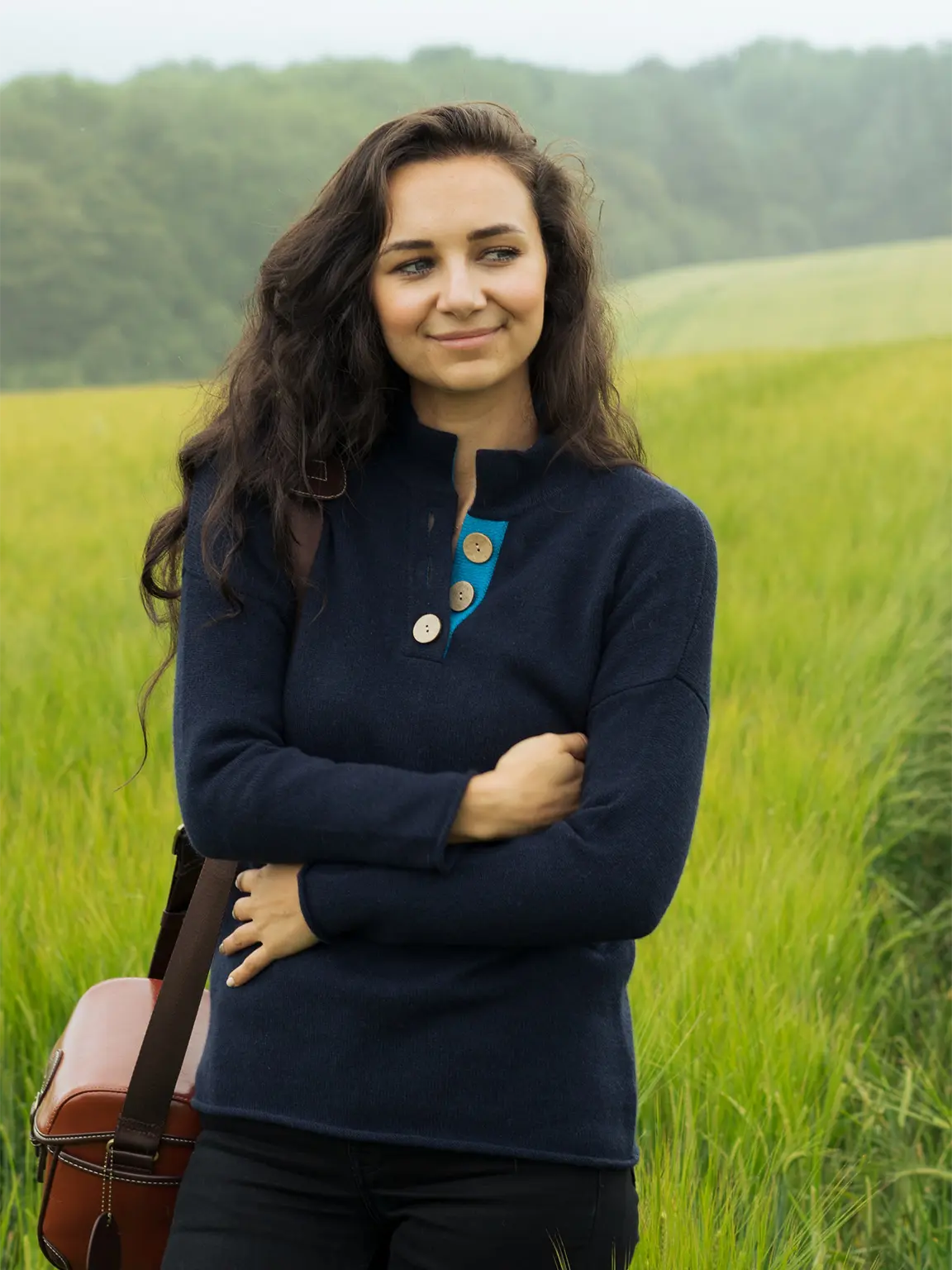 model standing in a field going for a walk wearing  the navy and turquoise high collar jumper sweater from misty cashmere