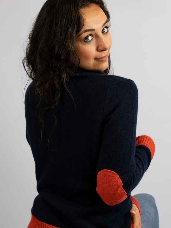 back view of model in navy roll neck jumper with burnt orange elbow patches cuff ends and hem