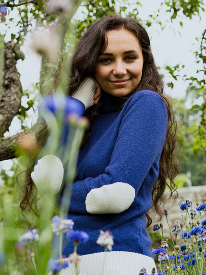 Women's roll neck jumper in blue with cream elbow patches, cuffs and bottom hem in cashmere merino by Misty Cashmere.