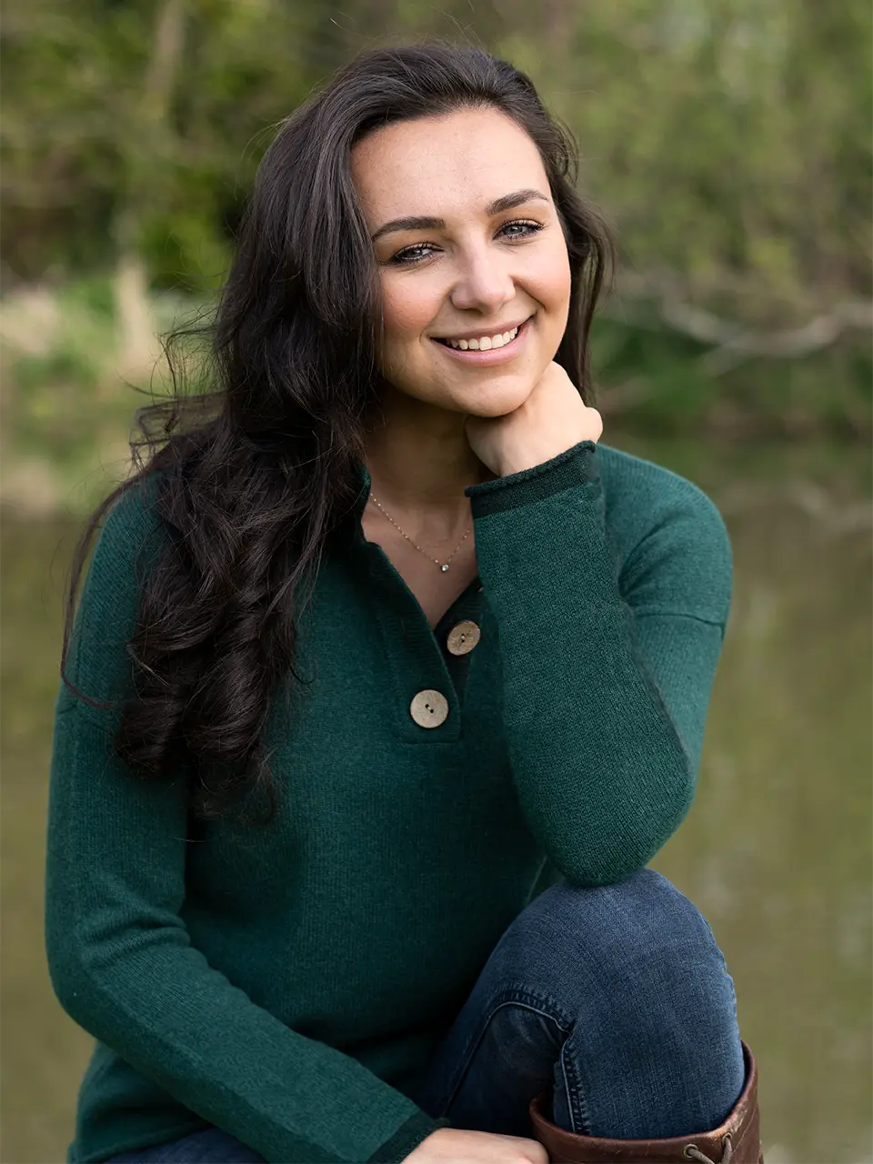 womans jumper in myrtle green sitting by river by misty cashmere